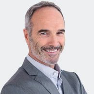 A man in a suit and tie smiling for the camera.